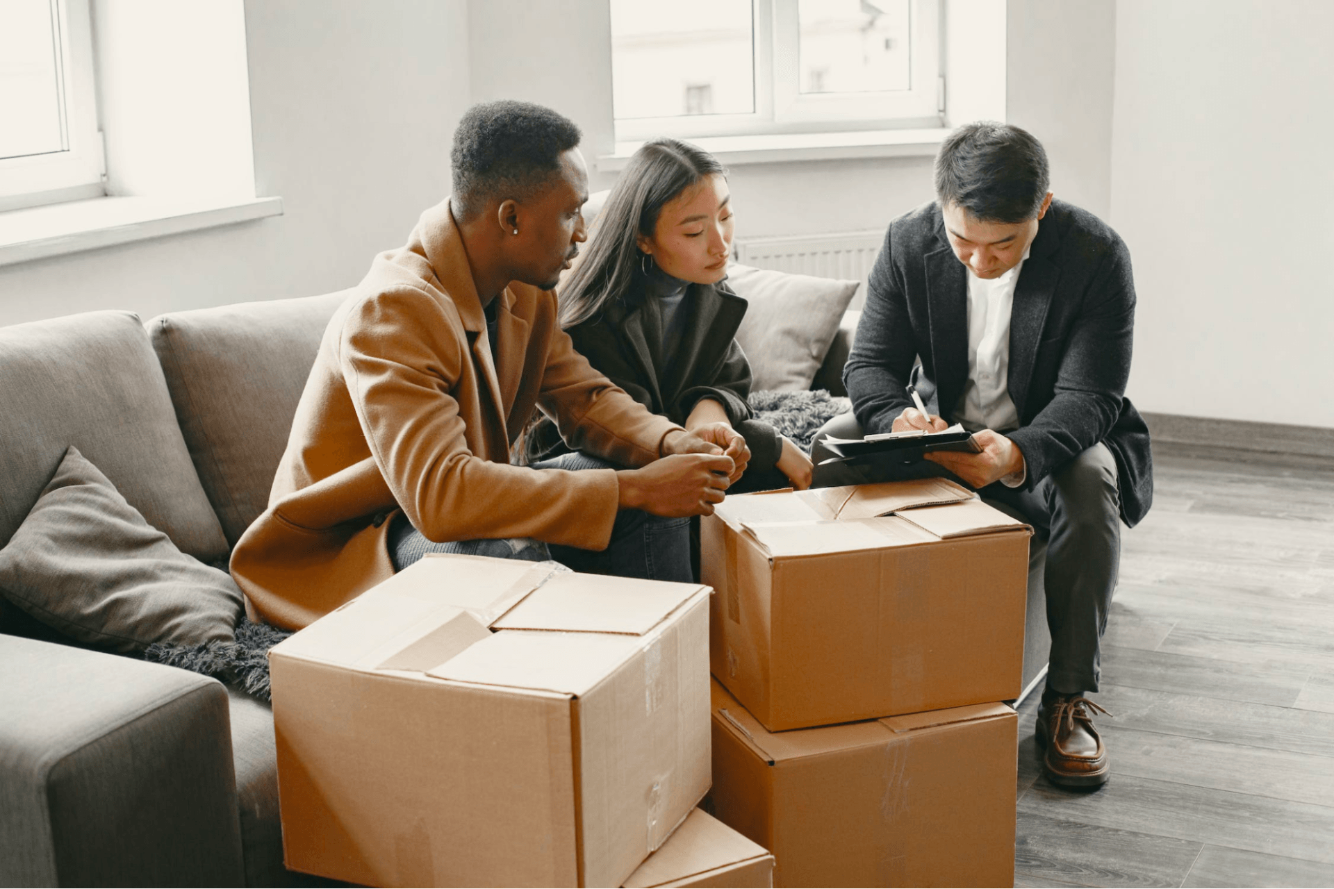 A group of people are sitting on a couch with cardboard boxes and looking at a tablet.