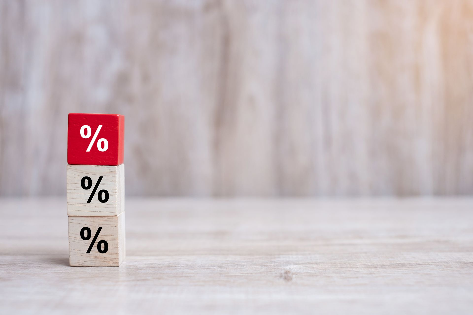 Three wooden blocks with percentages on them are stacked on top of each other on a wooden table.