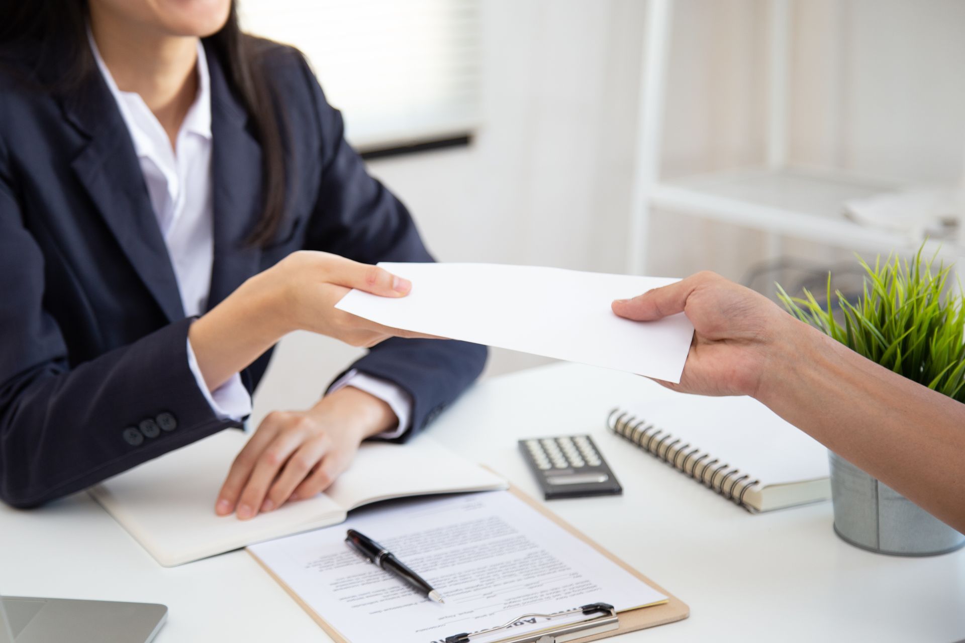 Payroll services professional handing a document to a client during an office consultation