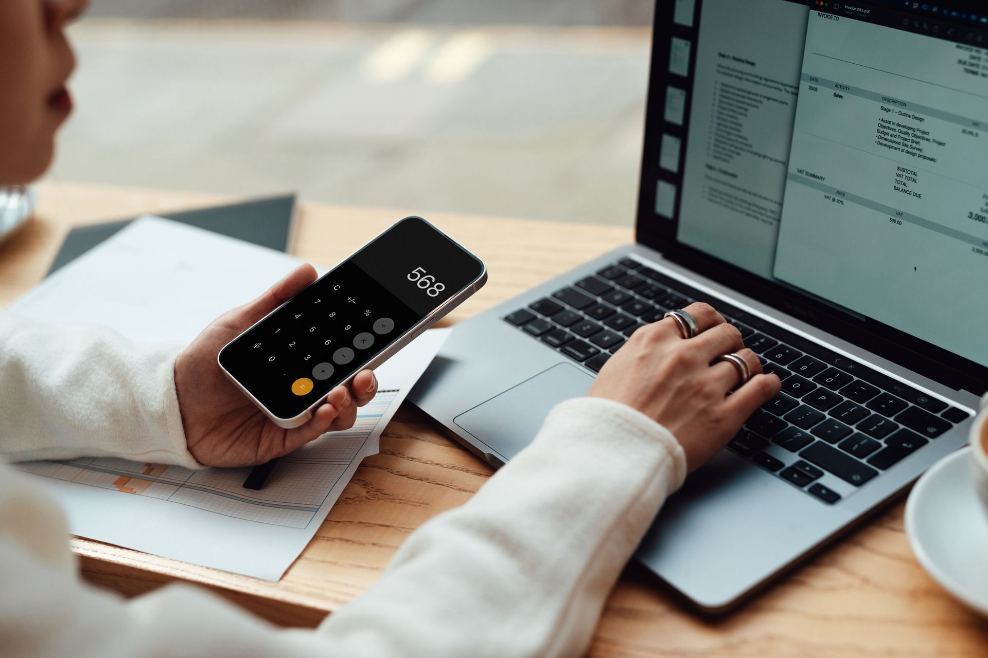Businesswoman calculating budget with smartphone while making financial plan via laptop. Businesswoman calculating budget with smartphone while making financial plan via laptop.