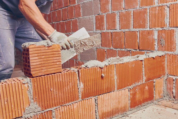 Real construction worker bricklaying the wall indoors
