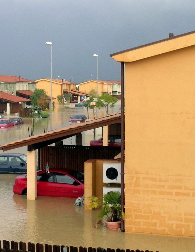 A flooded parking lot with a red car in it