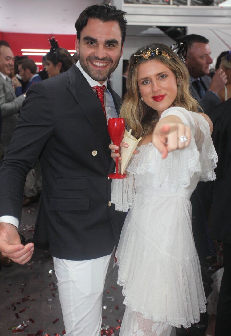 A man and a woman are posing for a picture and the woman is pointing at the camera