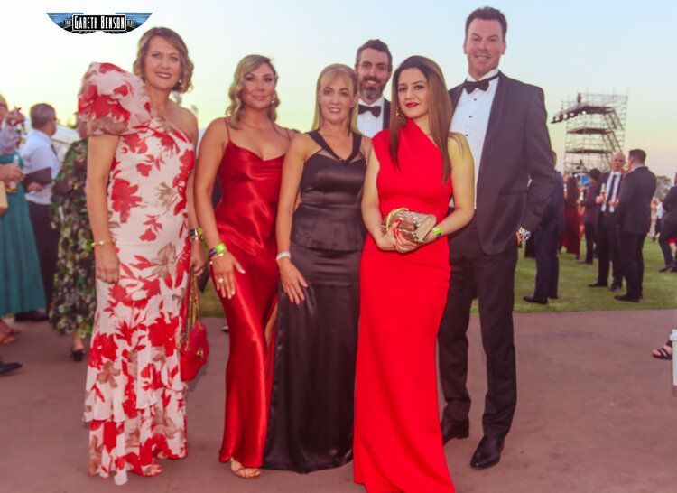 A group of people posing for a picture with one woman in a red dress