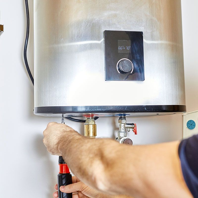 the man tightens the pipe nut in the water heating system. The master installs the water heater. The concept of bathroom maintenance