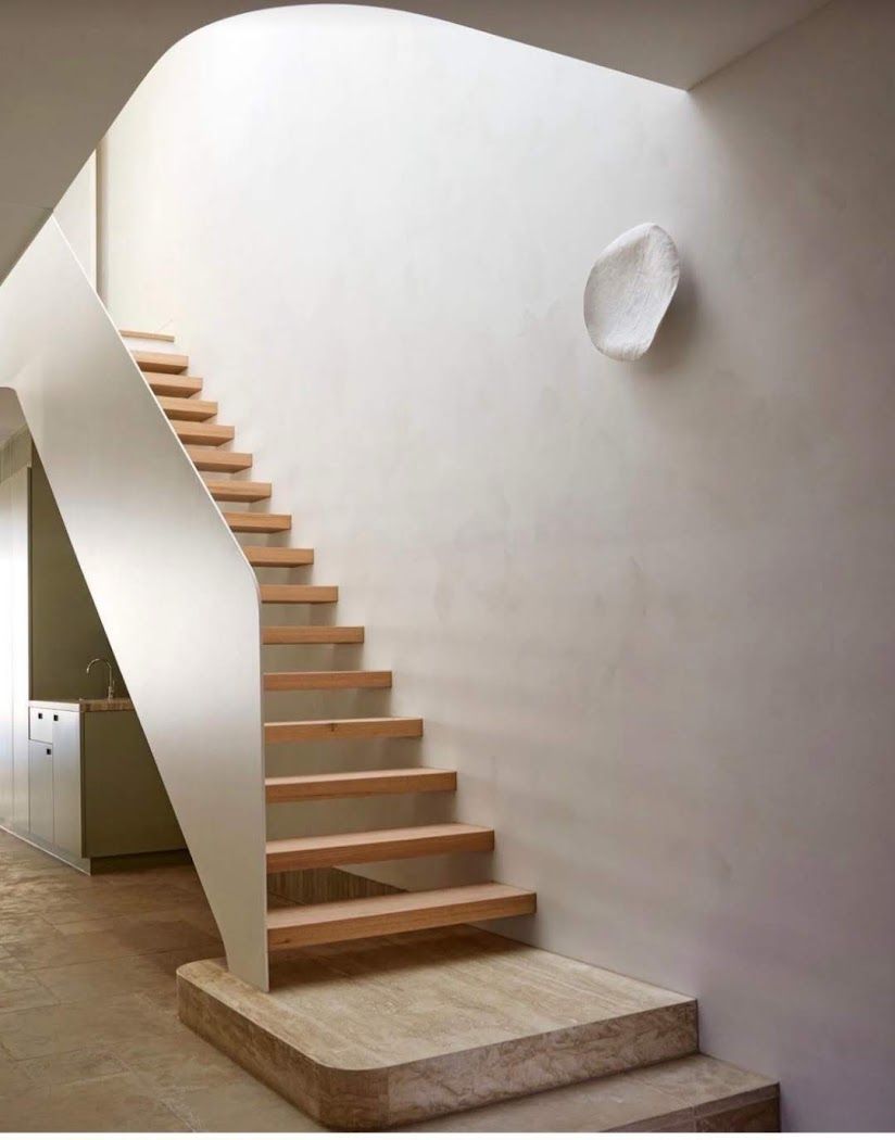 Modern indoor staircase with wooden steps, white walls, and a small wall-mounted light fixture