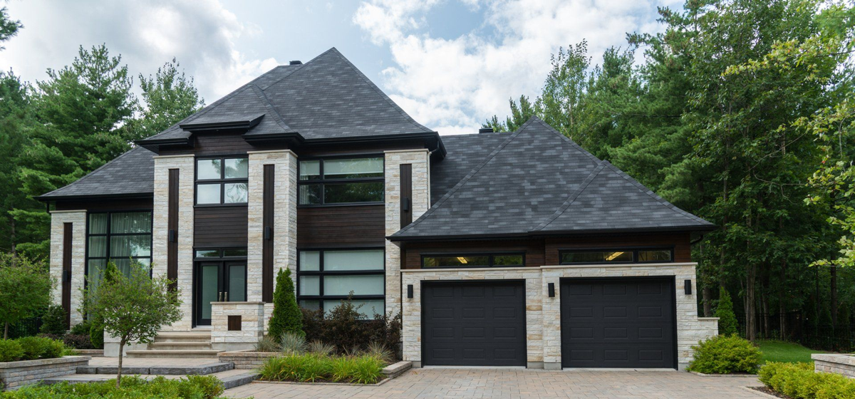 garage banner Modern two-story house with dark roof, two-car garage, and landscaped driveway