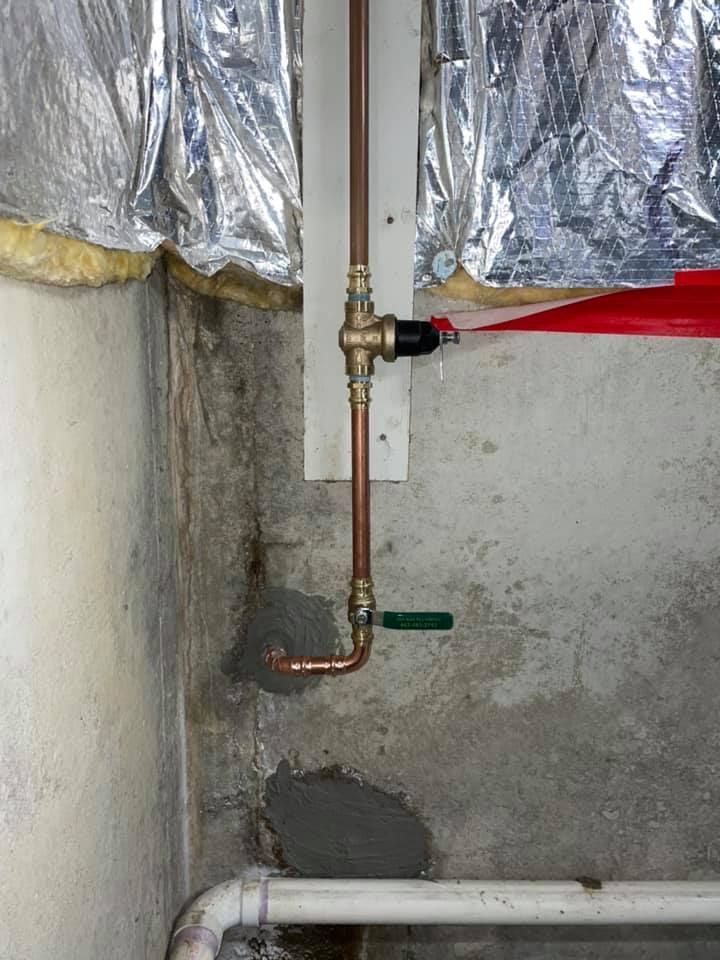 A close up of a copper pipe in a wall.