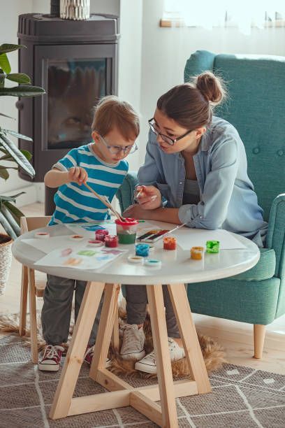 Child playing with paints next to therapist