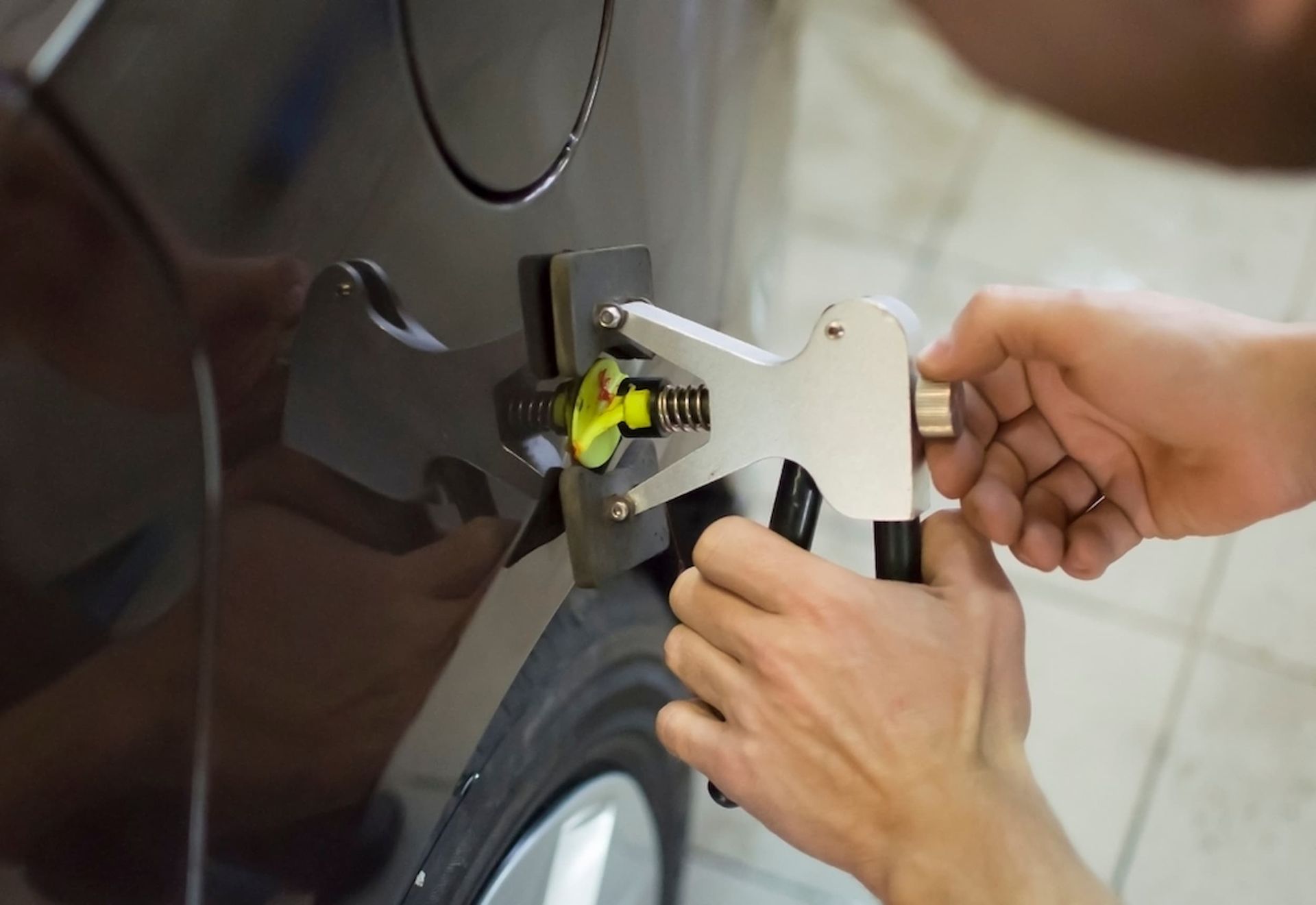 A Person Is Using a Tool to Remove a Dent from A Car — Chinderah Smash Repairs in Chinderah, NSW