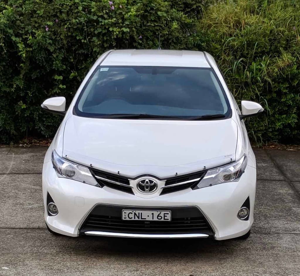 A White Toyota Car Is Parked in Front of A Bush — Chinderah Smash Repairs in Chinderah, NSW