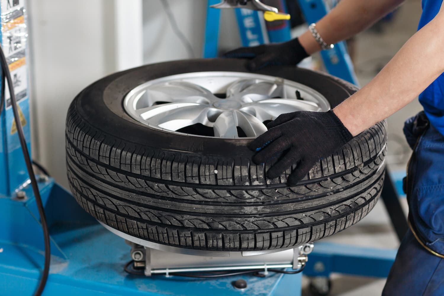 A Person Is Changing a Tire on A Machine in A Garage — Chinderah Smash Repairs in Chinderah, NSW