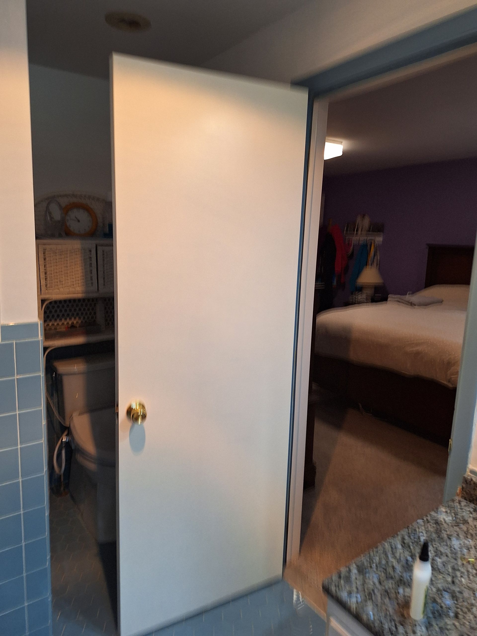 White door ajar, reveals a laundry area and a bedroom.