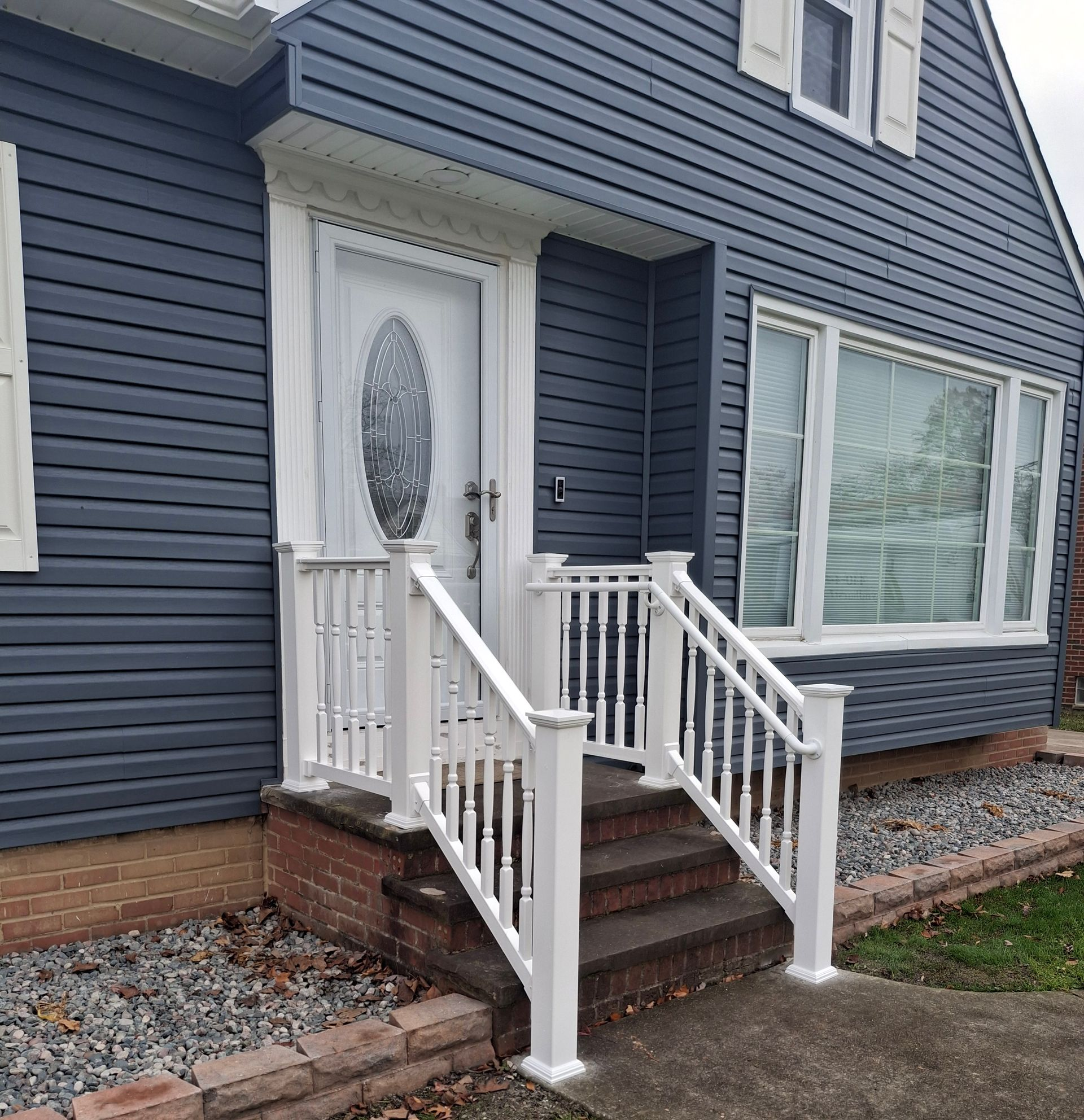 Blue-sided house with white trim, porch, steps, and decorative front door.