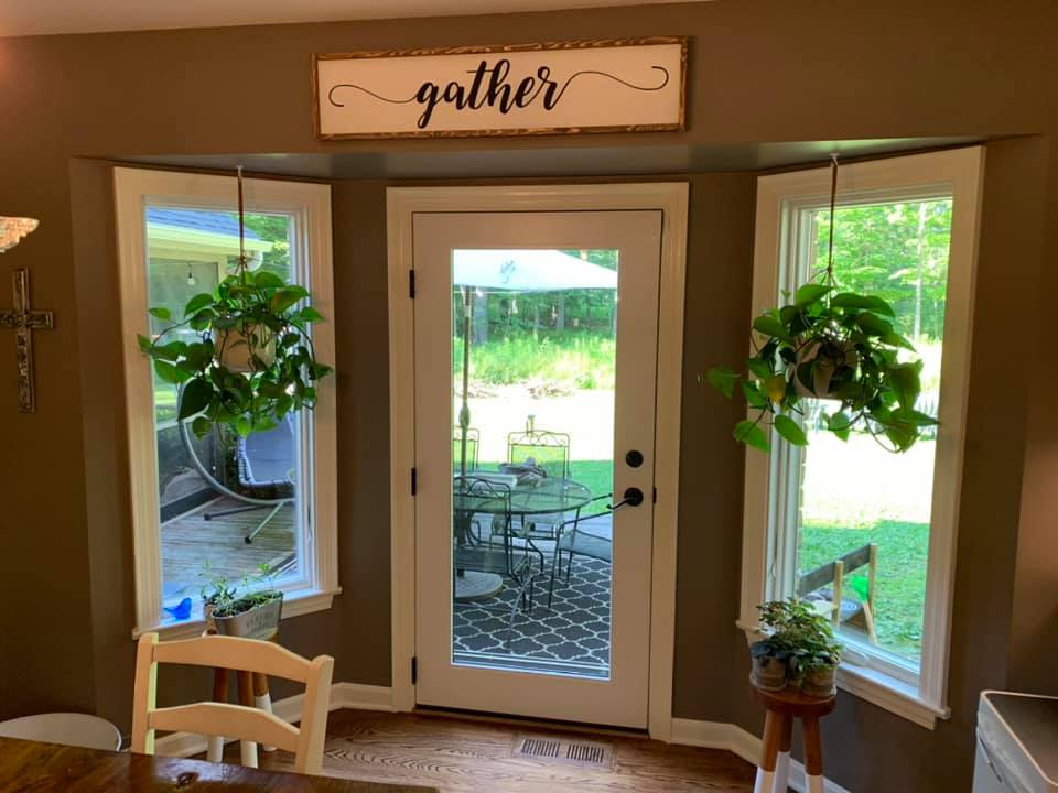 A doorway flanked by windows, with hanging plants and a 
