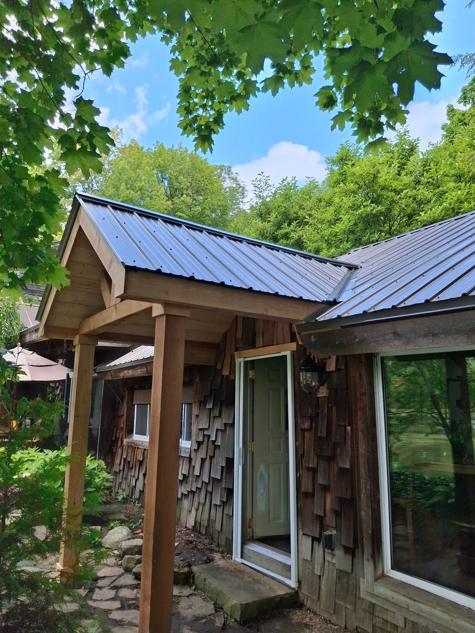 Rustic cabin with brown wood shake siding and metal roof under blue sky.