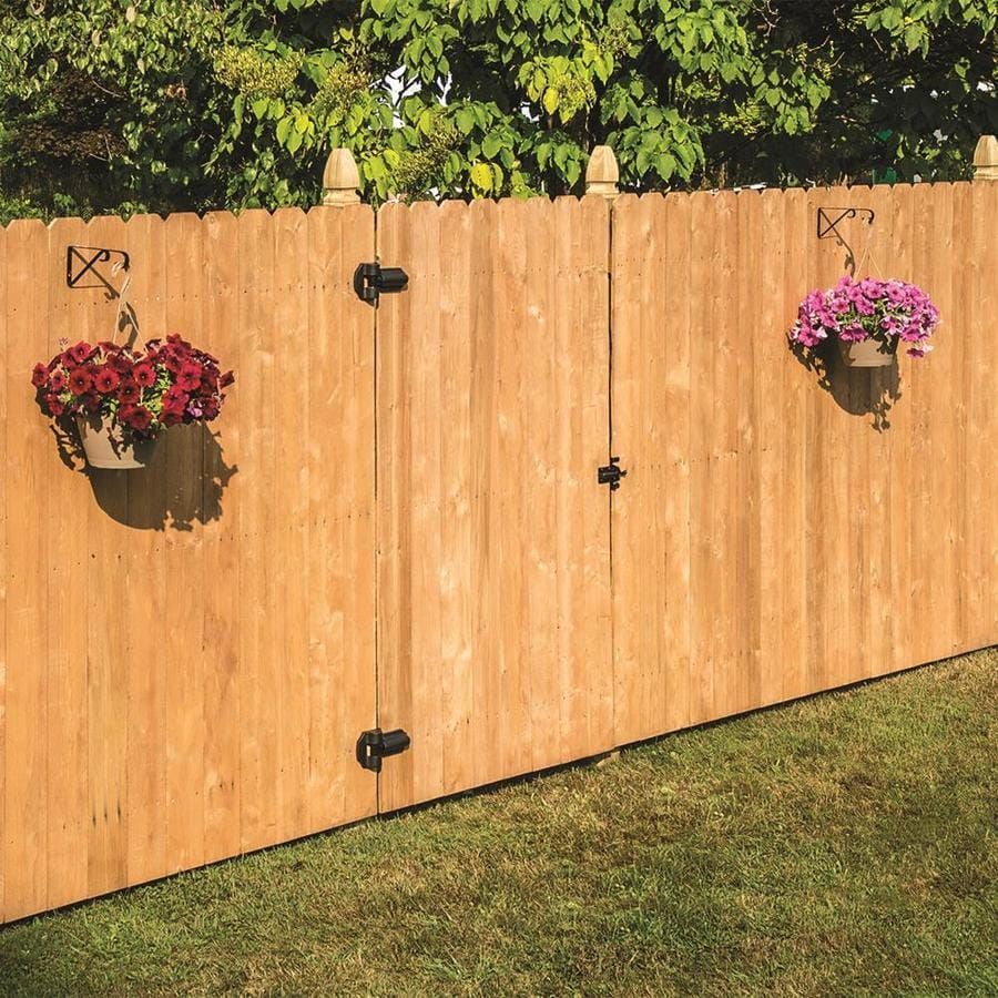 Wooden fence with hanging flower pots and a gate in a grassy yard.