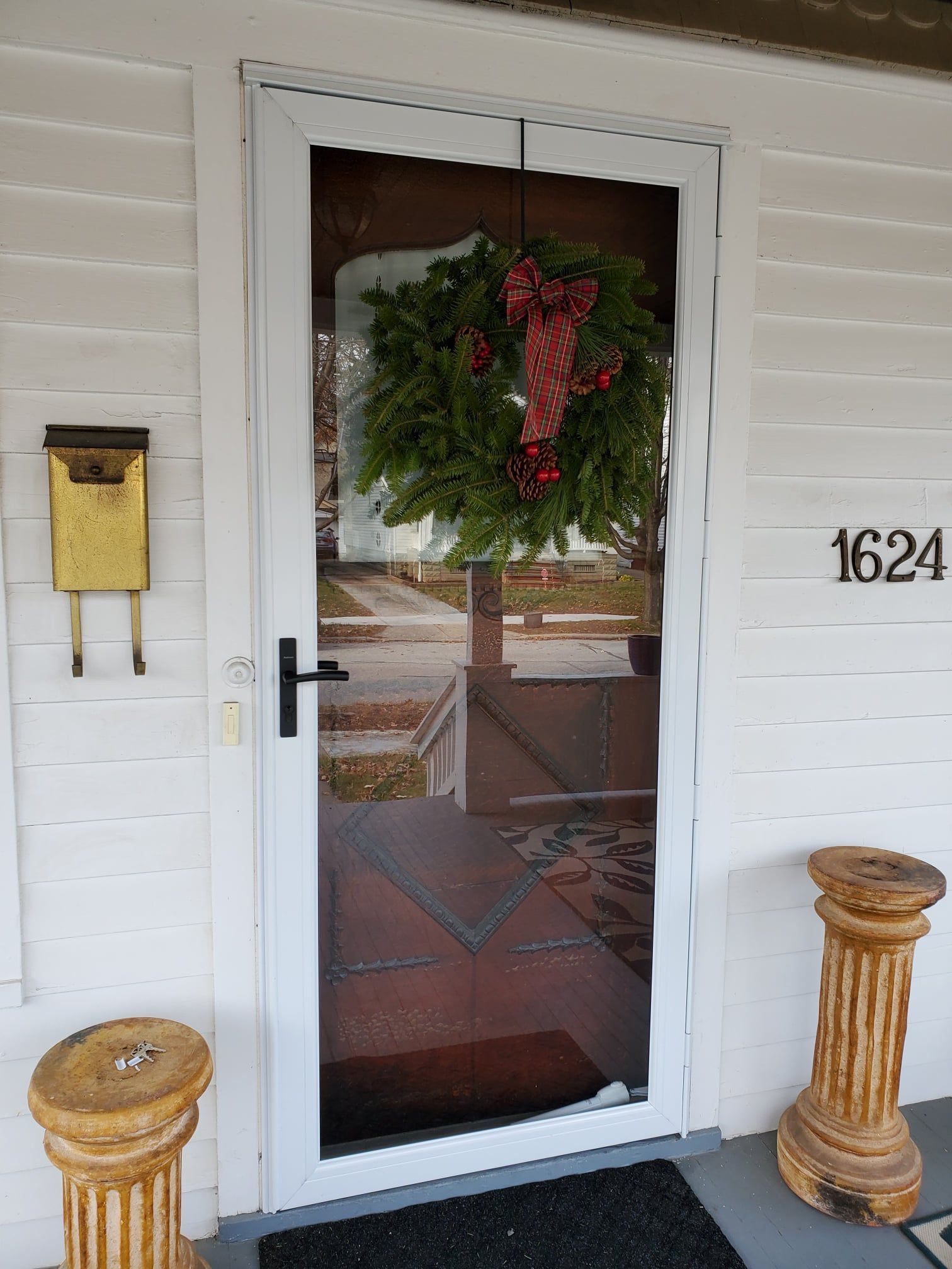 White door with screen and wreath, golden mailbox, and columns. House number 1624.