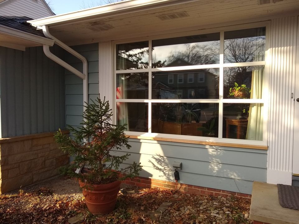 Exterior view of a house with large windows, potted plant, and light blue siding.