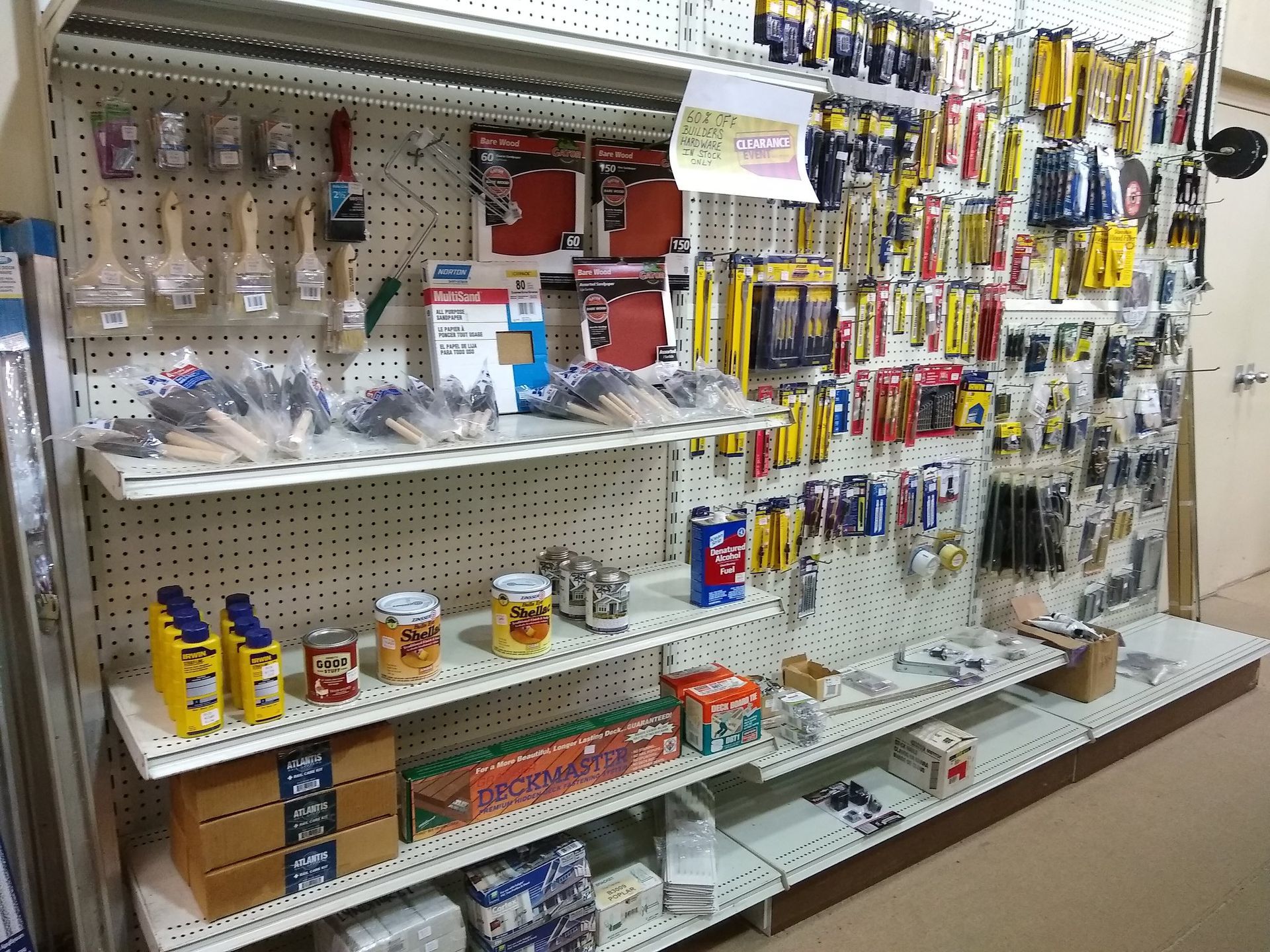 Shelves stocked with hardware tools and supplies in a store setting.