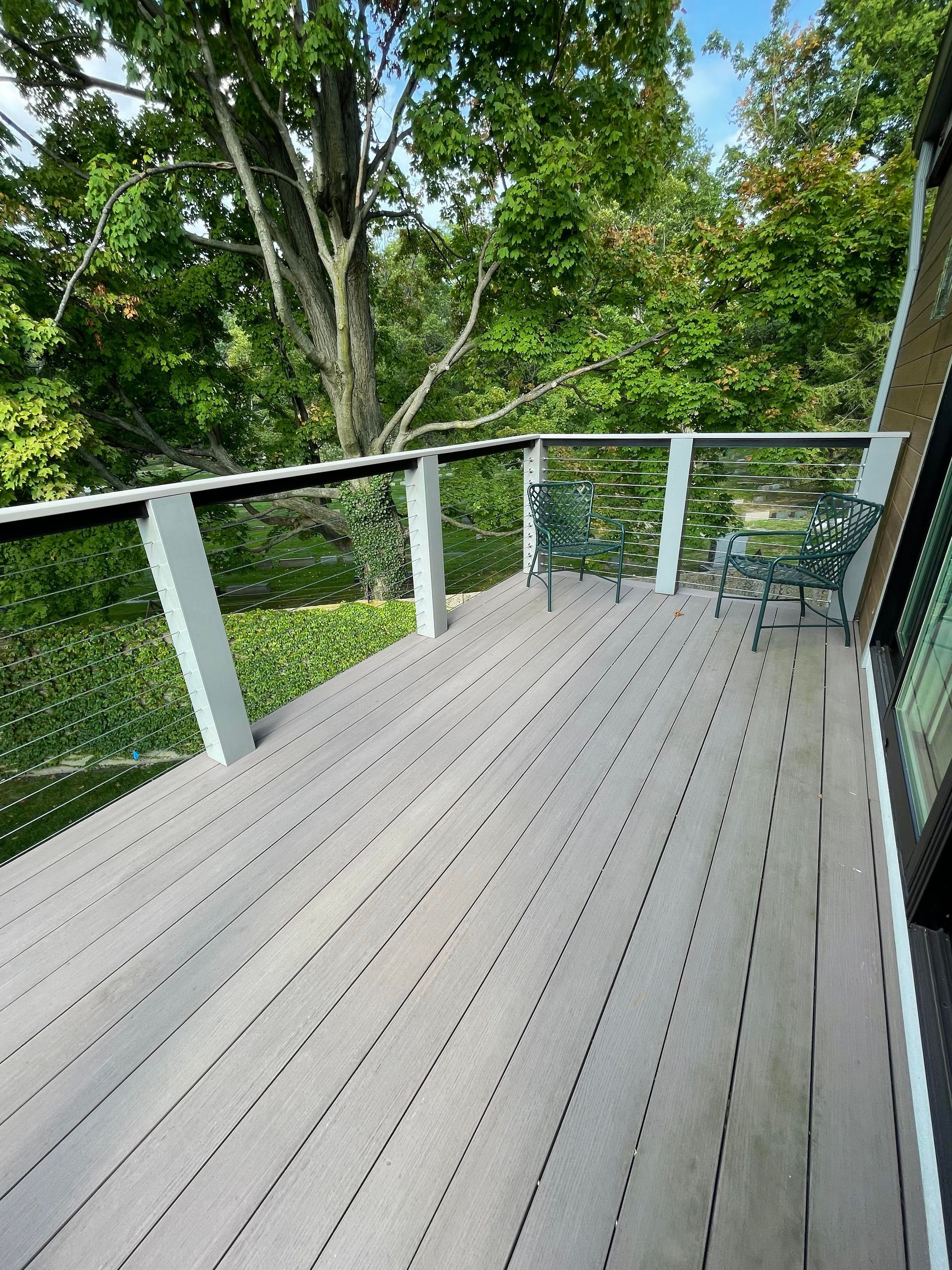Deck with composite decking and cable railing overlooking a wooded area.