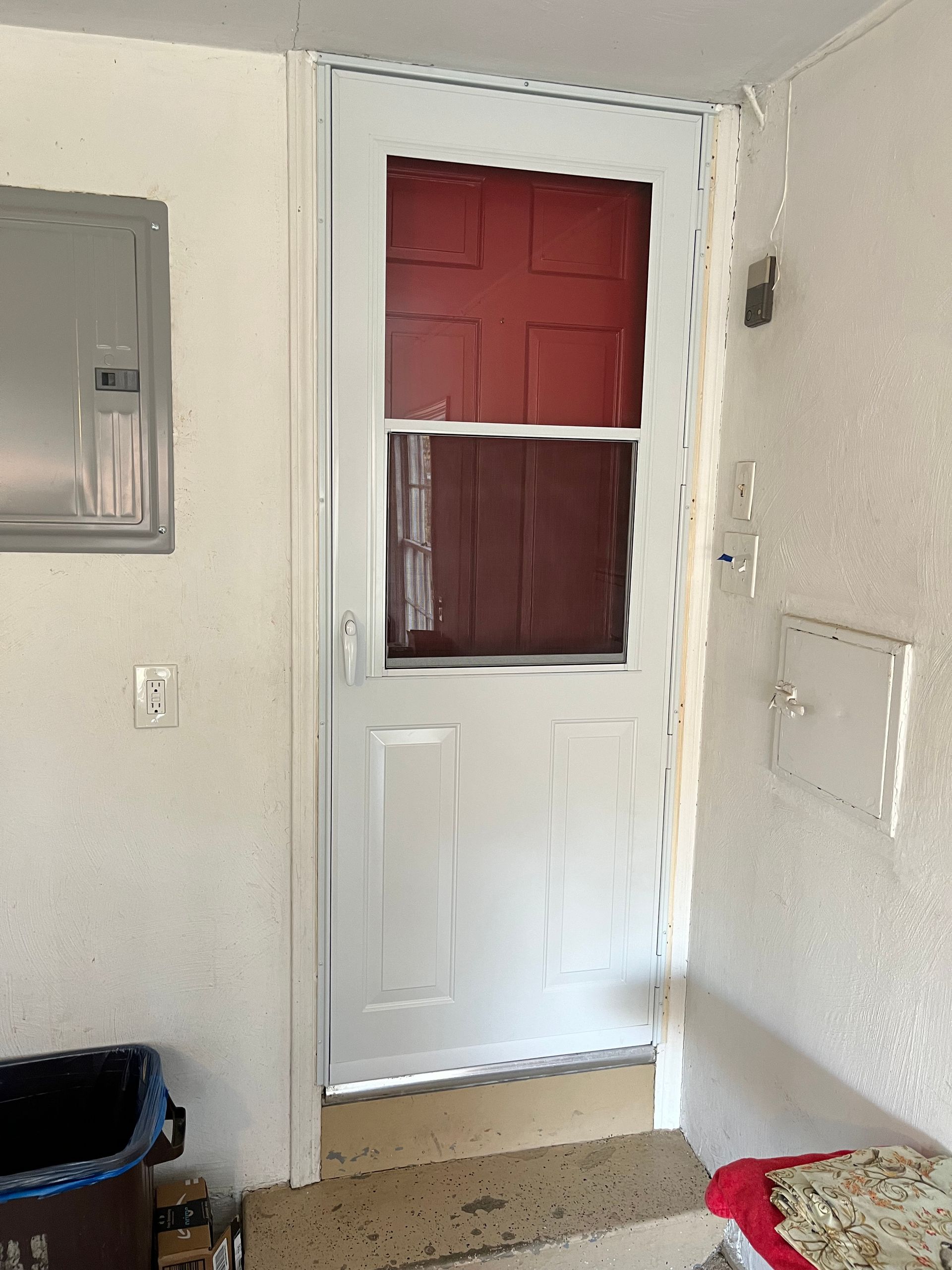 White screen door with red interior door visible, set in a white painted doorway.