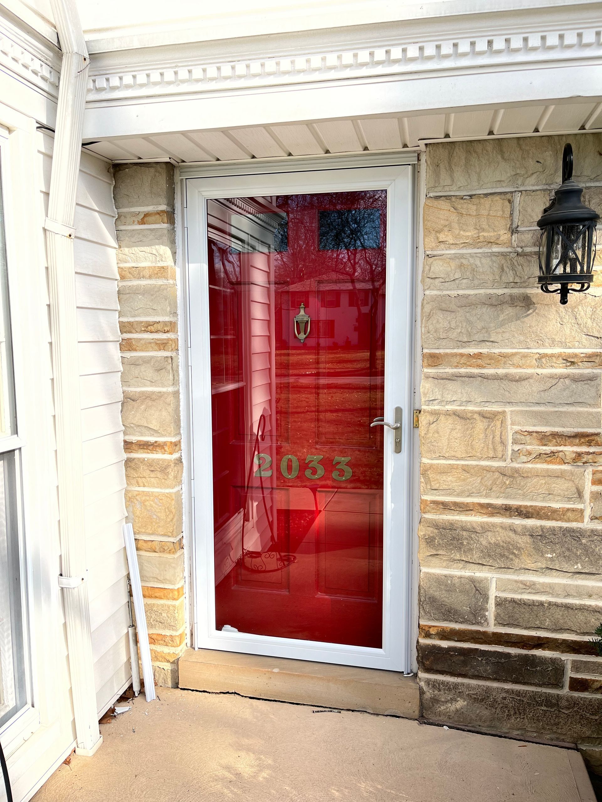 White-framed storm door on a stone building with address numbers 