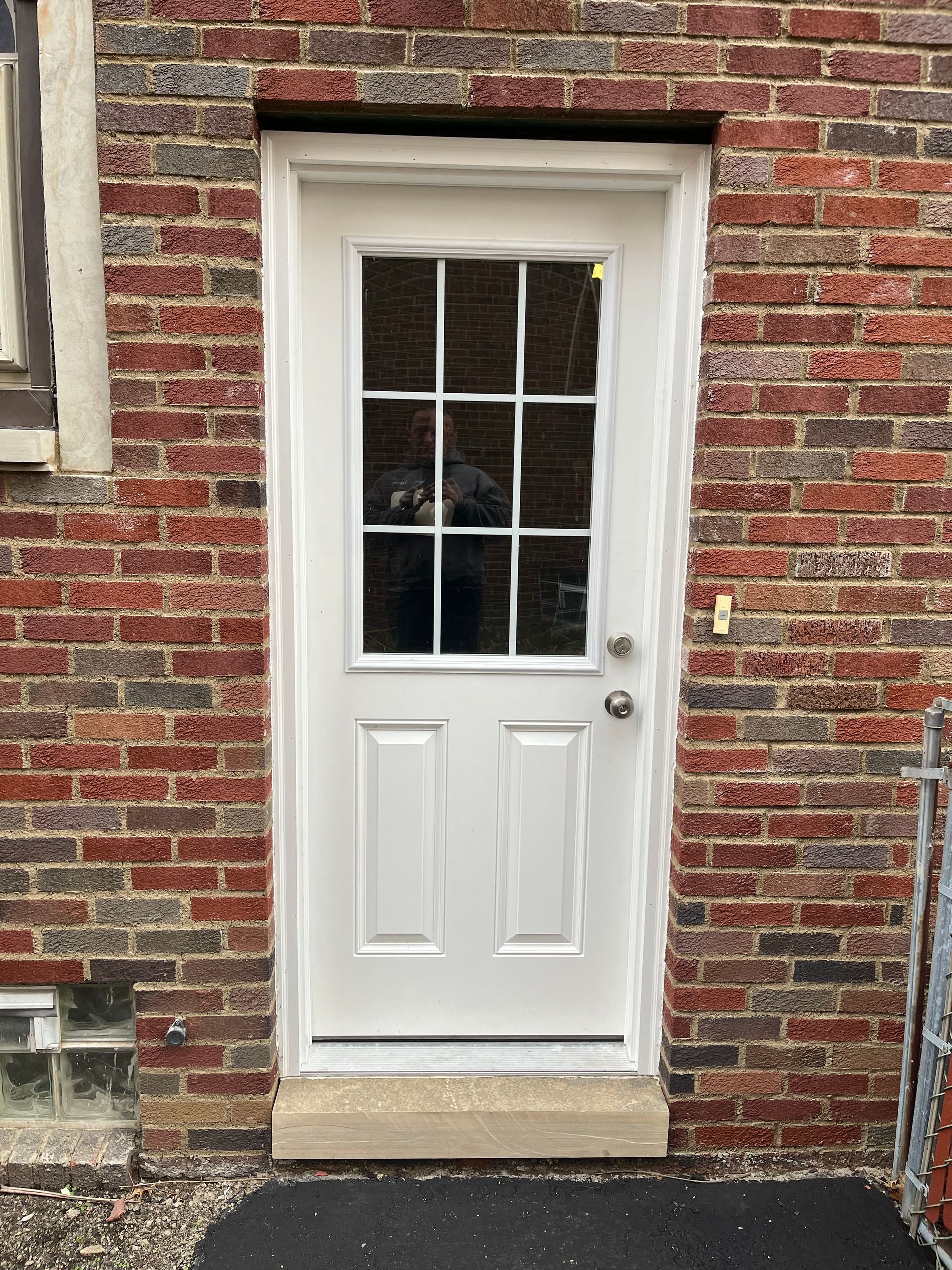 White exterior door with glass panes set into red brick wall.
