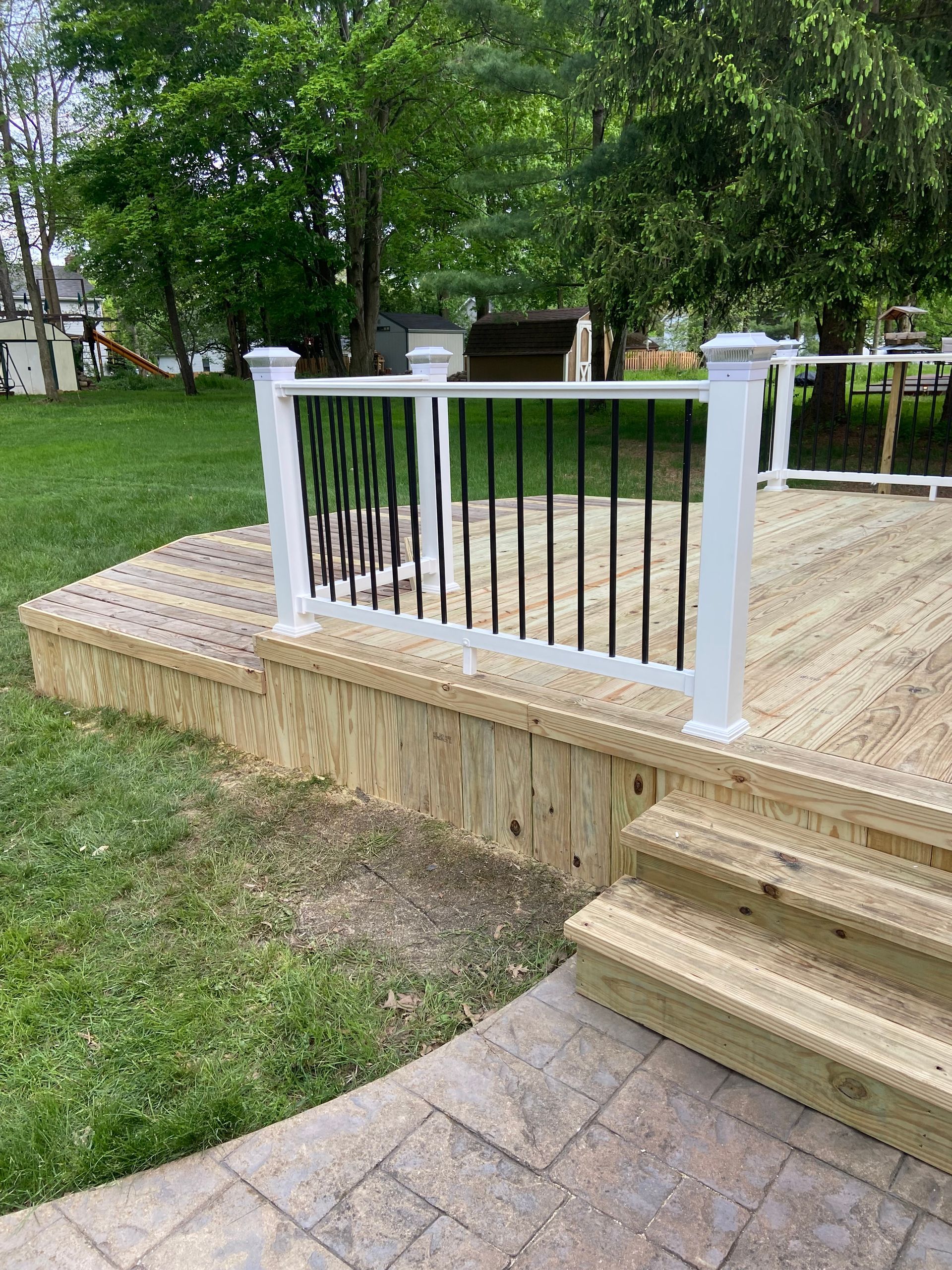 Wooden deck with white railing and black vertical bars; outdoor setting.