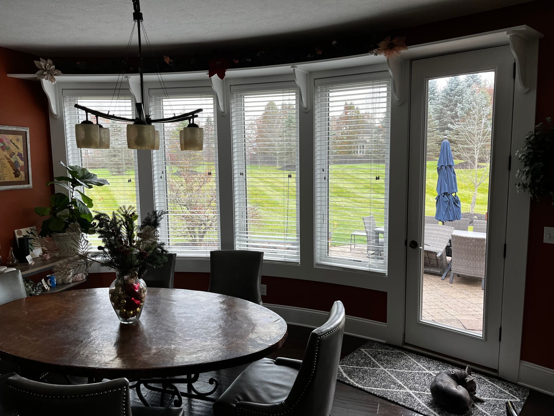 Dining room with round table, chairs, windows, and a view of a yard.