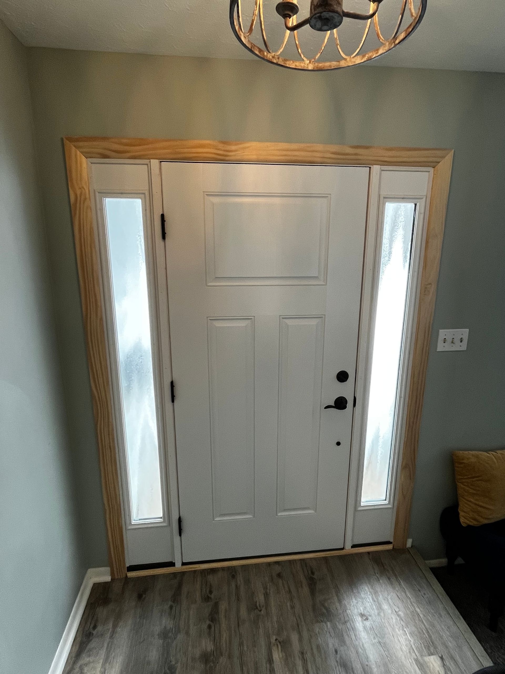White front door with frosted sidelights, framed in wood, interior view.