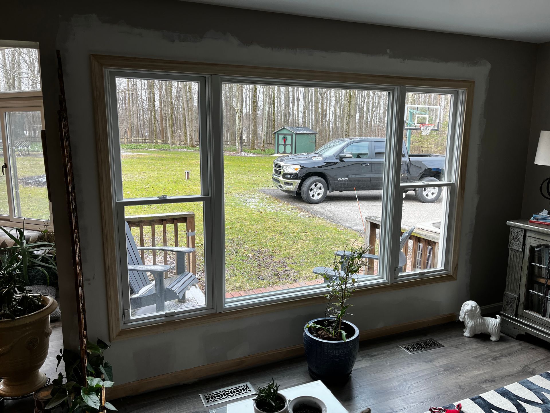 Large window looking out to a truck parked on grass, with interior plant and furnishings in view.