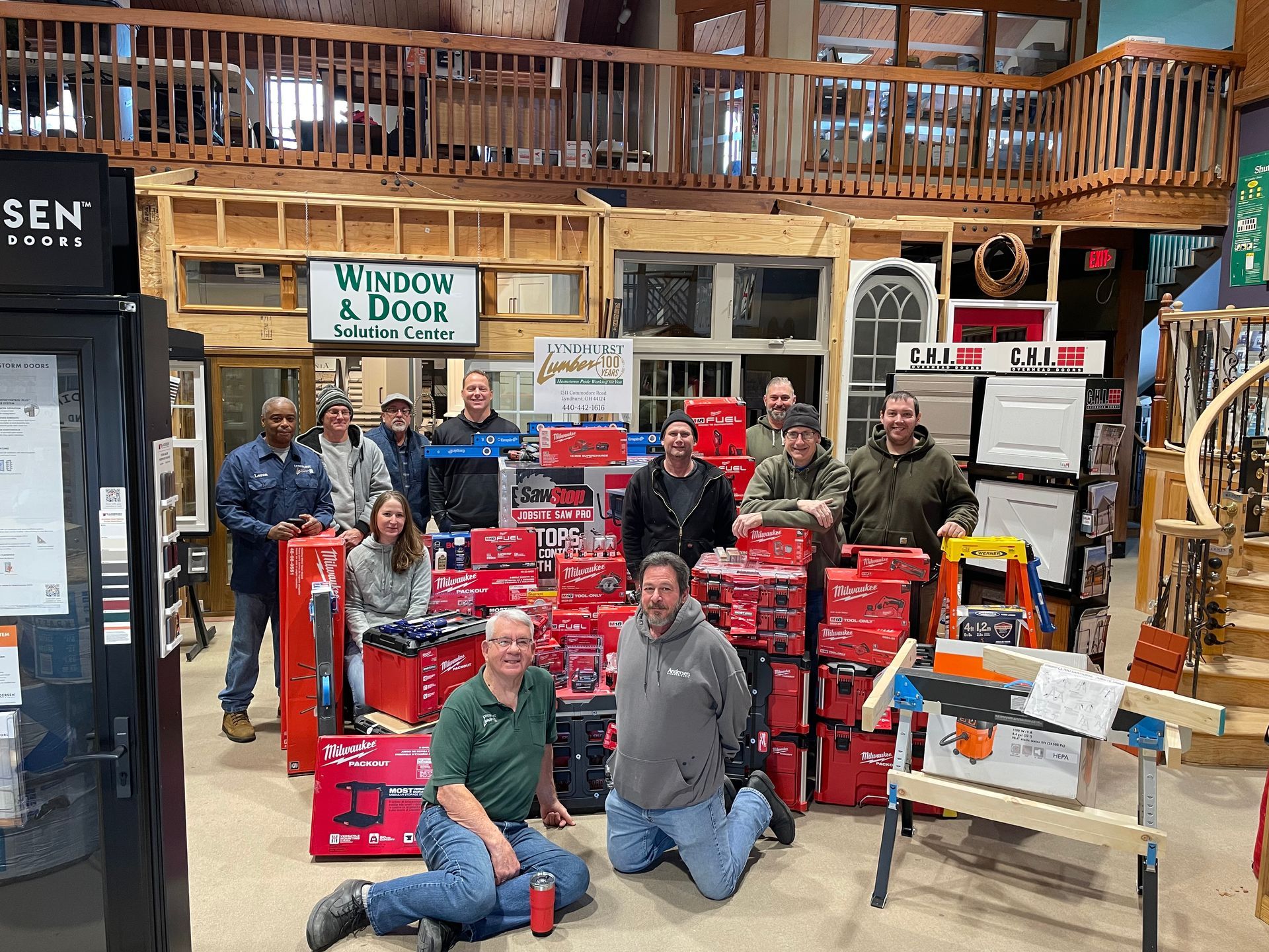Group of people in a store surrounded by red toolboxes, smiling and posing.