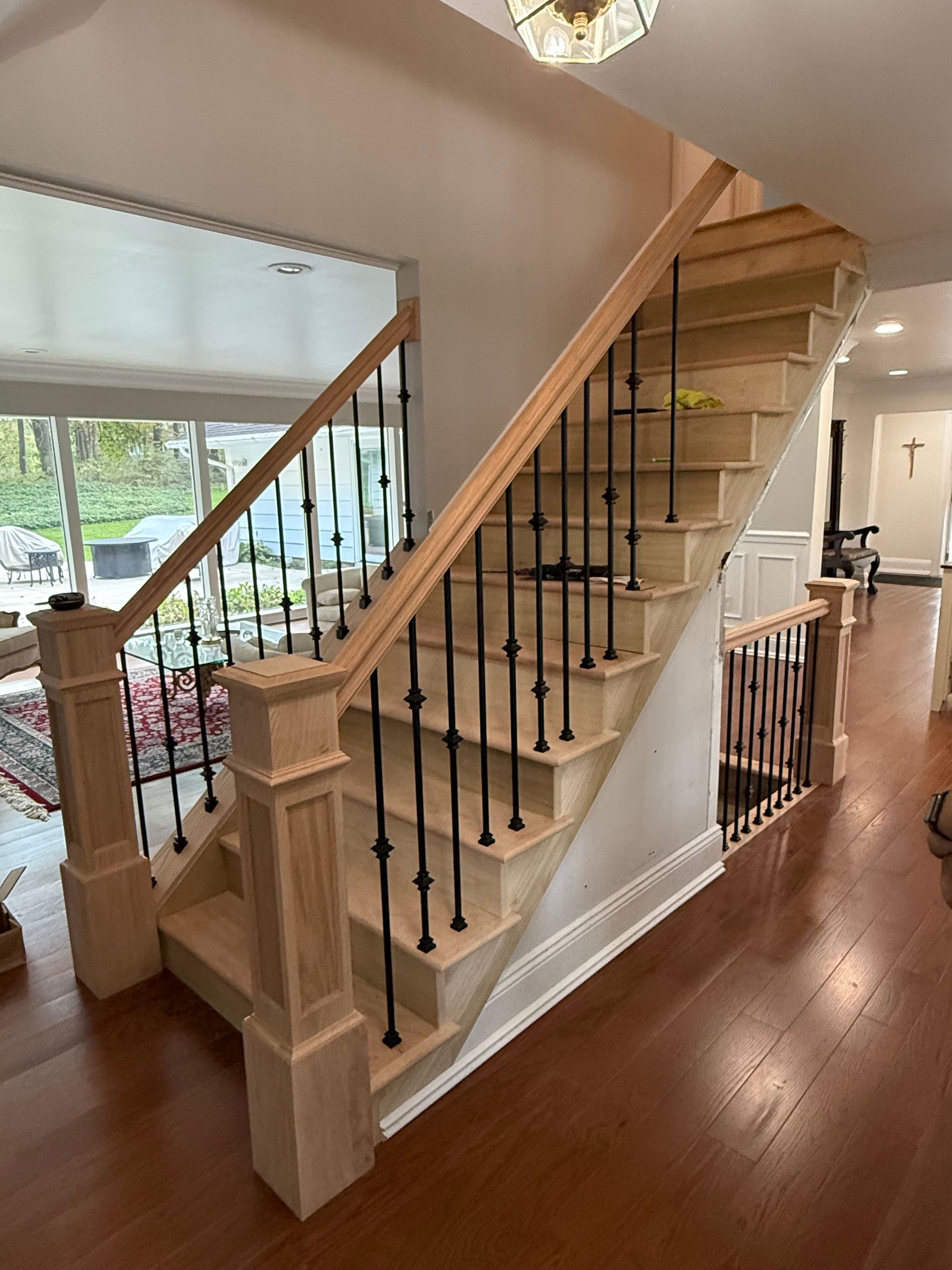 Wooden staircase with black metal balusters, natural light, and hardwood floors.