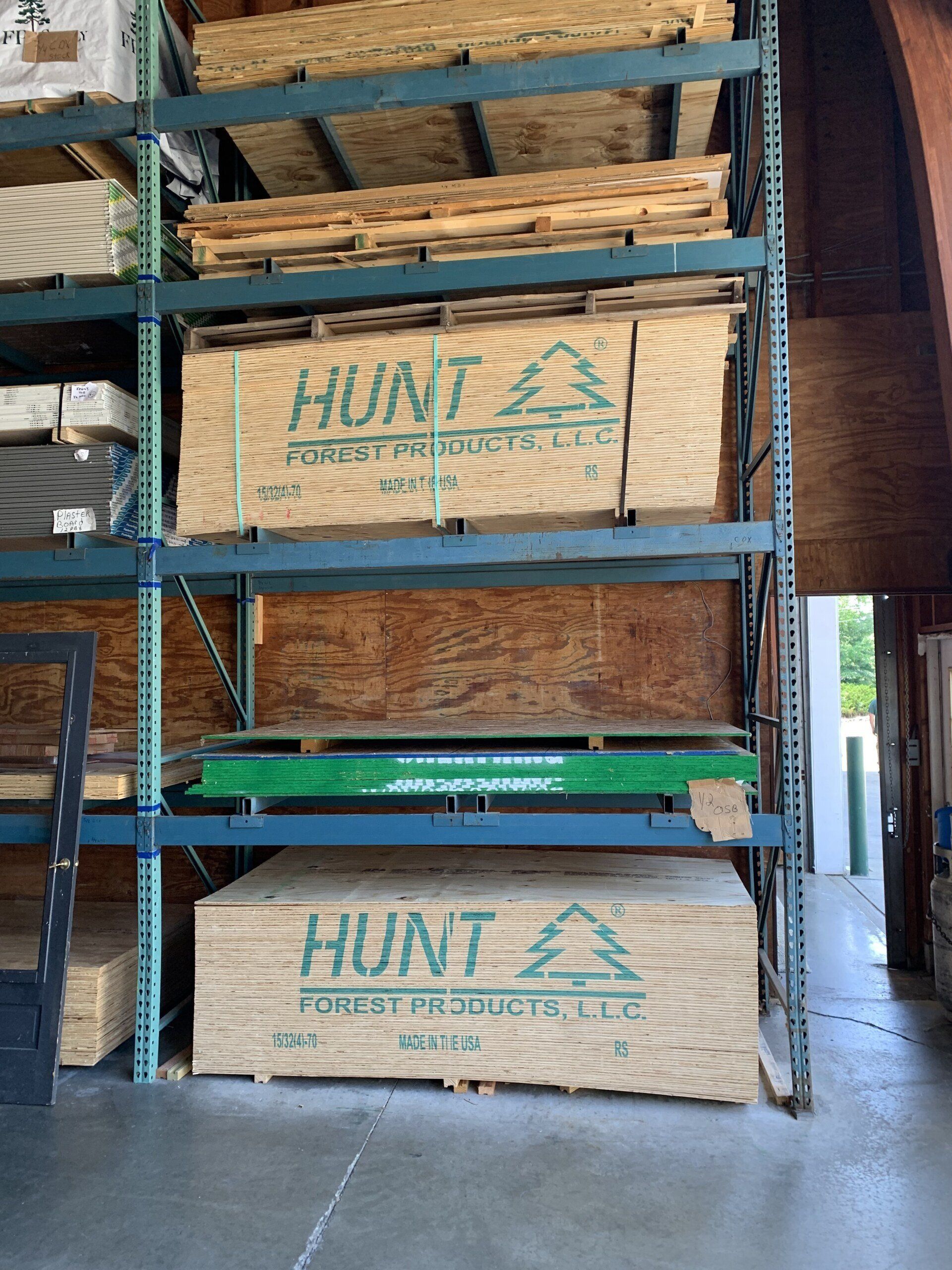 Shelves stacked with wood products, including plywood bearing the 