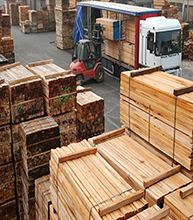 Forklift loading lumber onto a truck at a lumberyard.