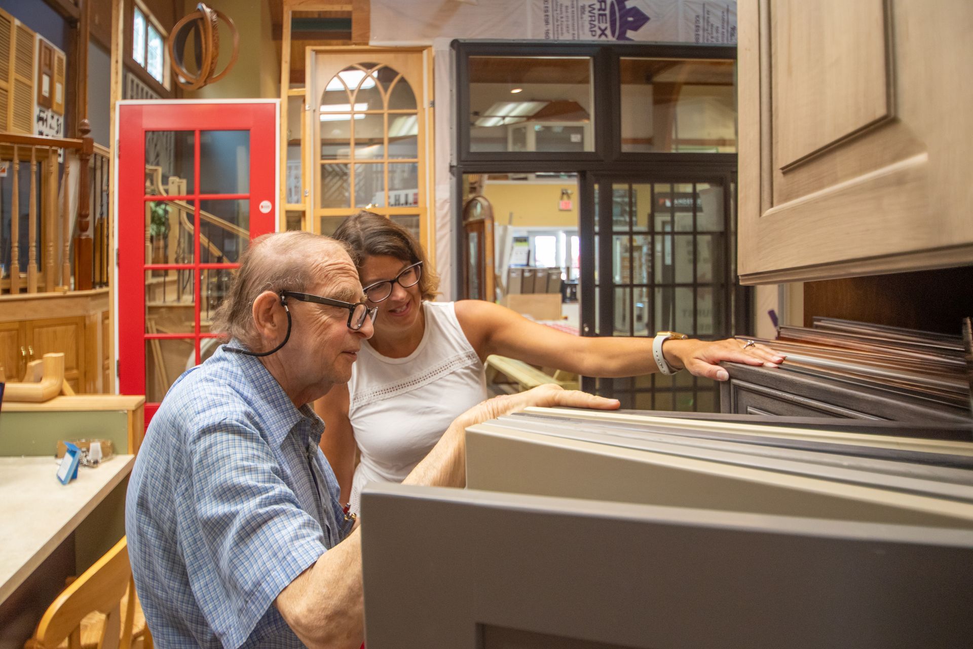 A person assists a customer with cabinet samples in a showroom.