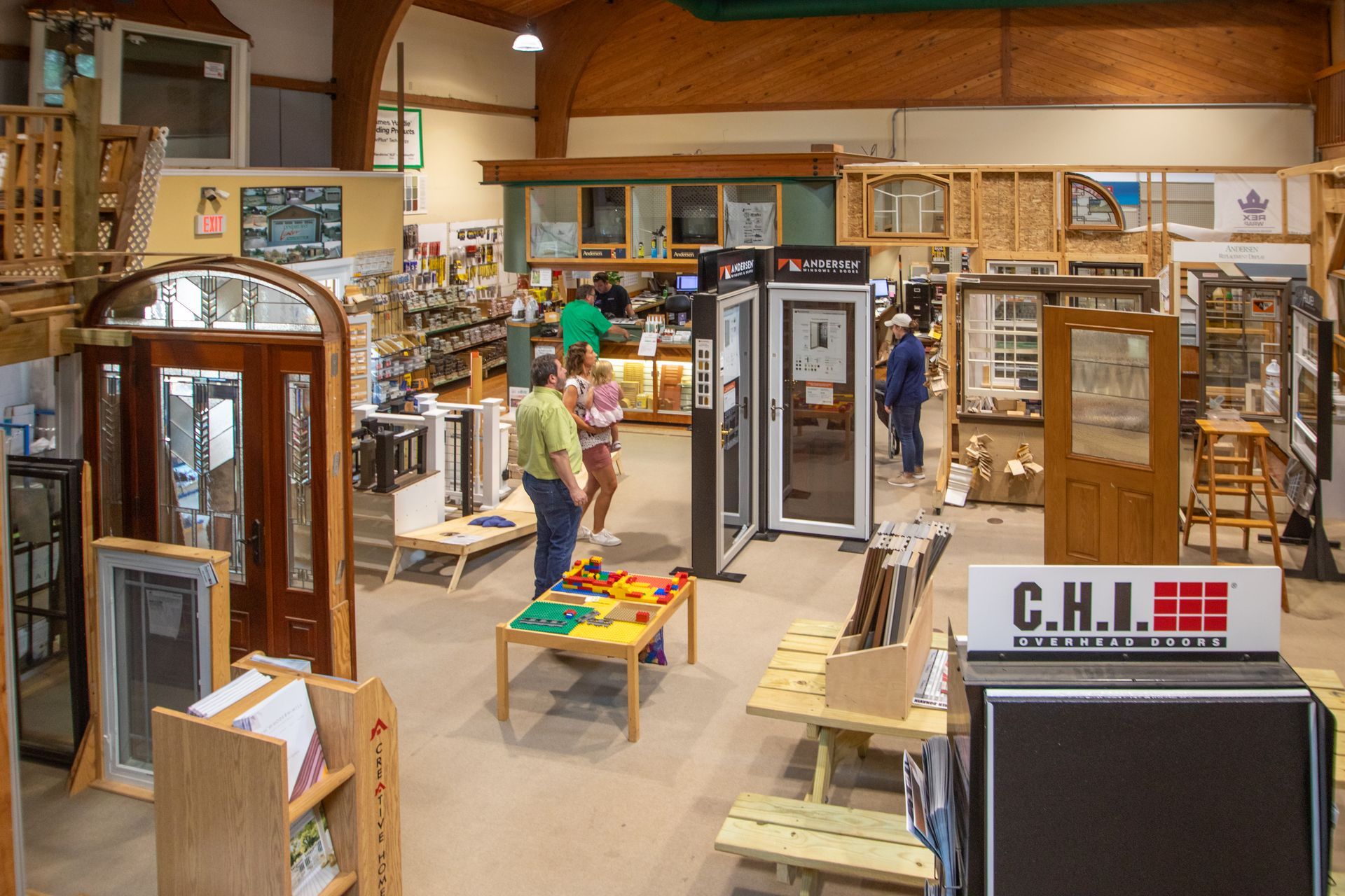 Interior of a door and window store, showcasing various display models; customers browse.