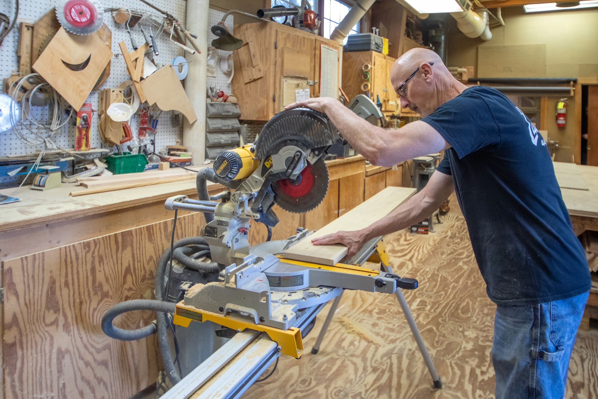Man using a miter saw in a workshop to cut a piece of wood.