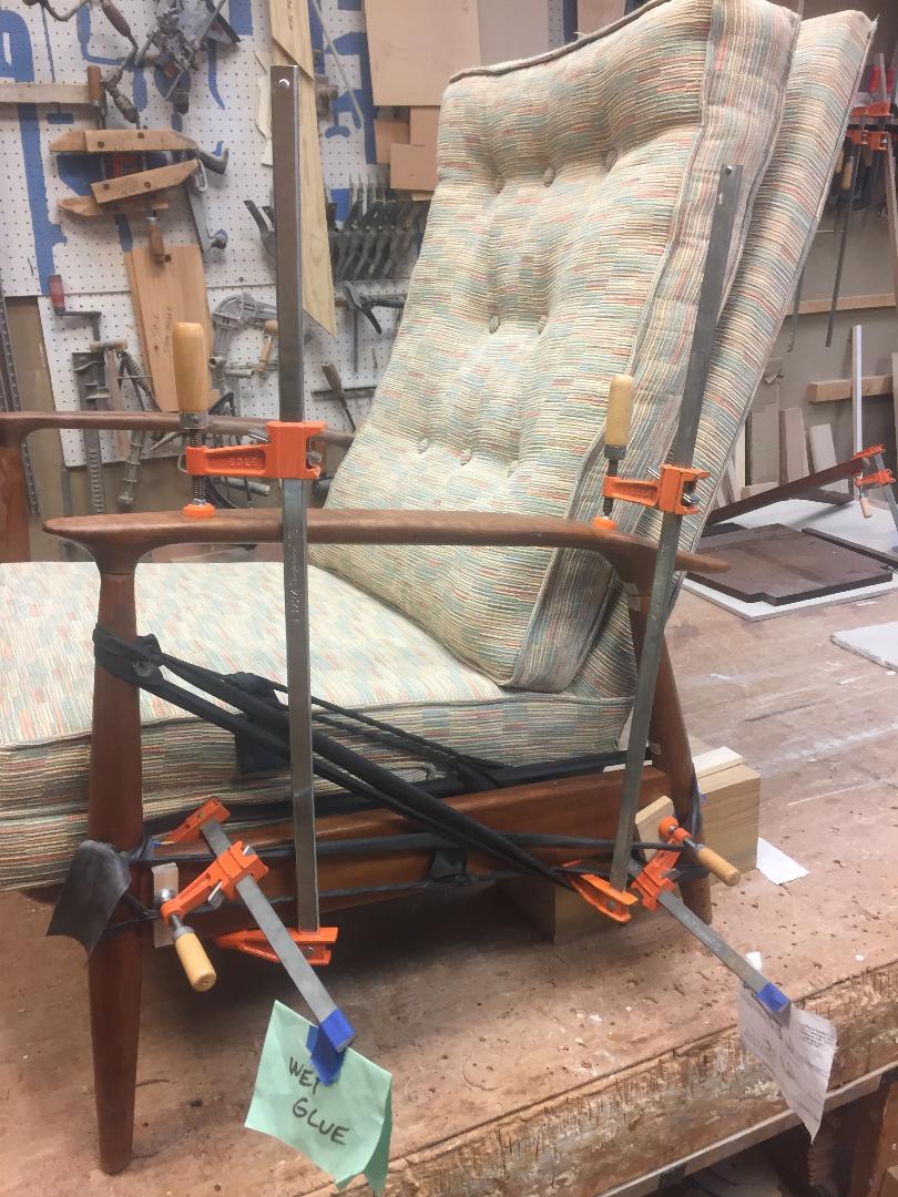 Chair being repaired with clamps, in a workshop.
