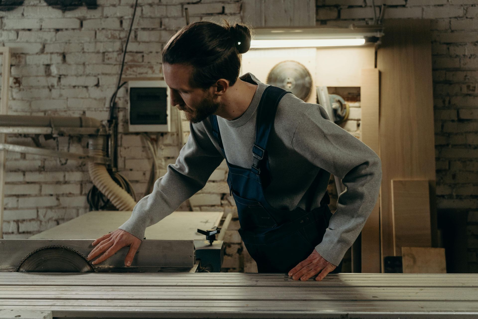 A man is working on a circular saw in a workshop.