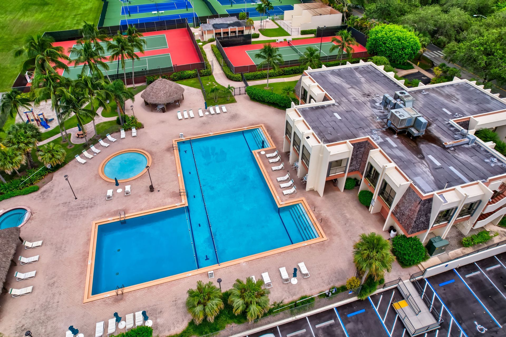 An aerial view of a swimming pool and tennis courts