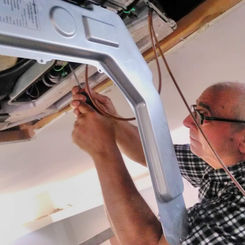 Un tecnico stringe i fili di un apparecchio montato a soffitto con una chiave inglese.