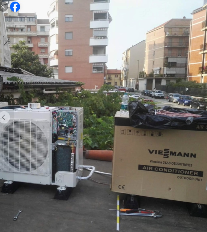 Unità HVAC esterne e un condizionatore Viessmann installato su un tetto, con edifici residenziali nelle vicinanze.