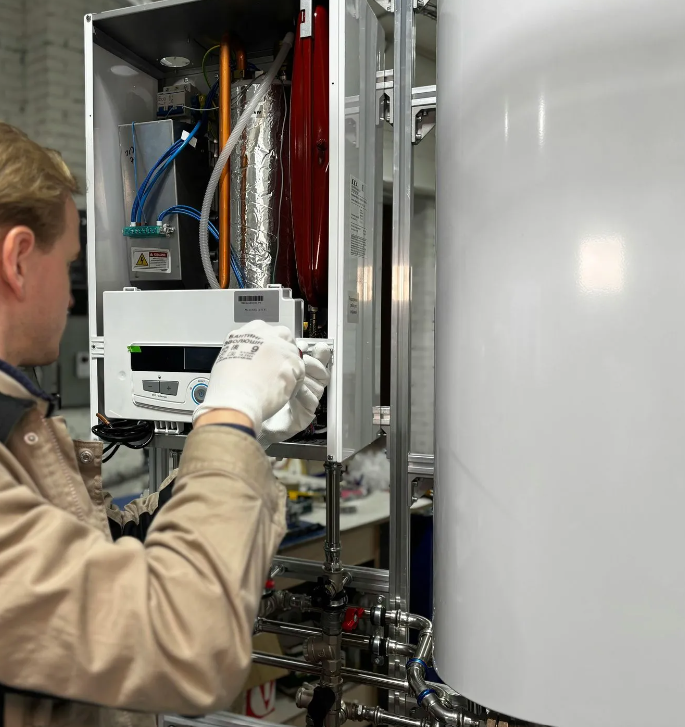 Un tecnico regola un'apparecchiatura di laboratorio accanto a una grande vasca bianca e al relativo pannello di controllo.