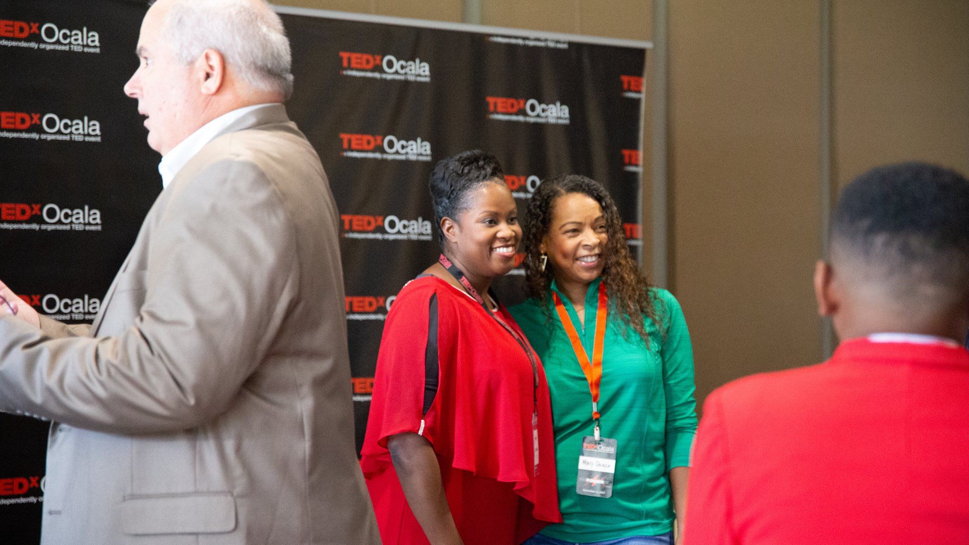 A group of people posing for a picture in front of a ted talk backdrop