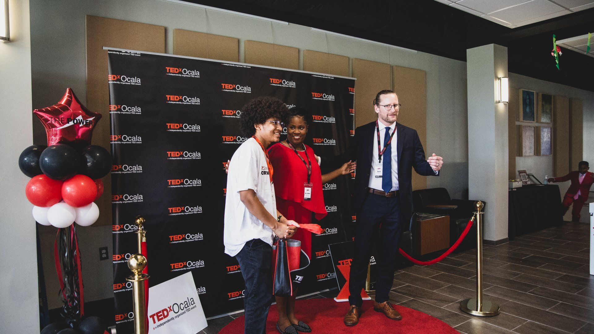 A group of people are standing on a red carpet.