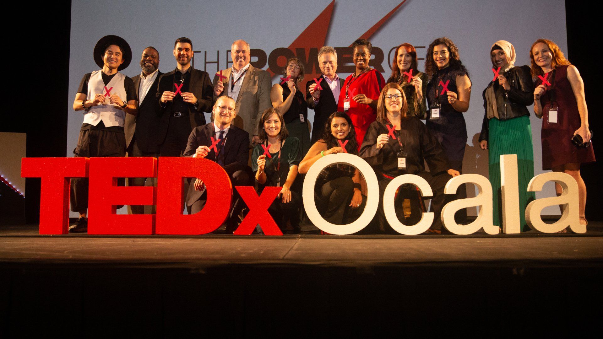 A group of people standing in front of a tedx ocala sign