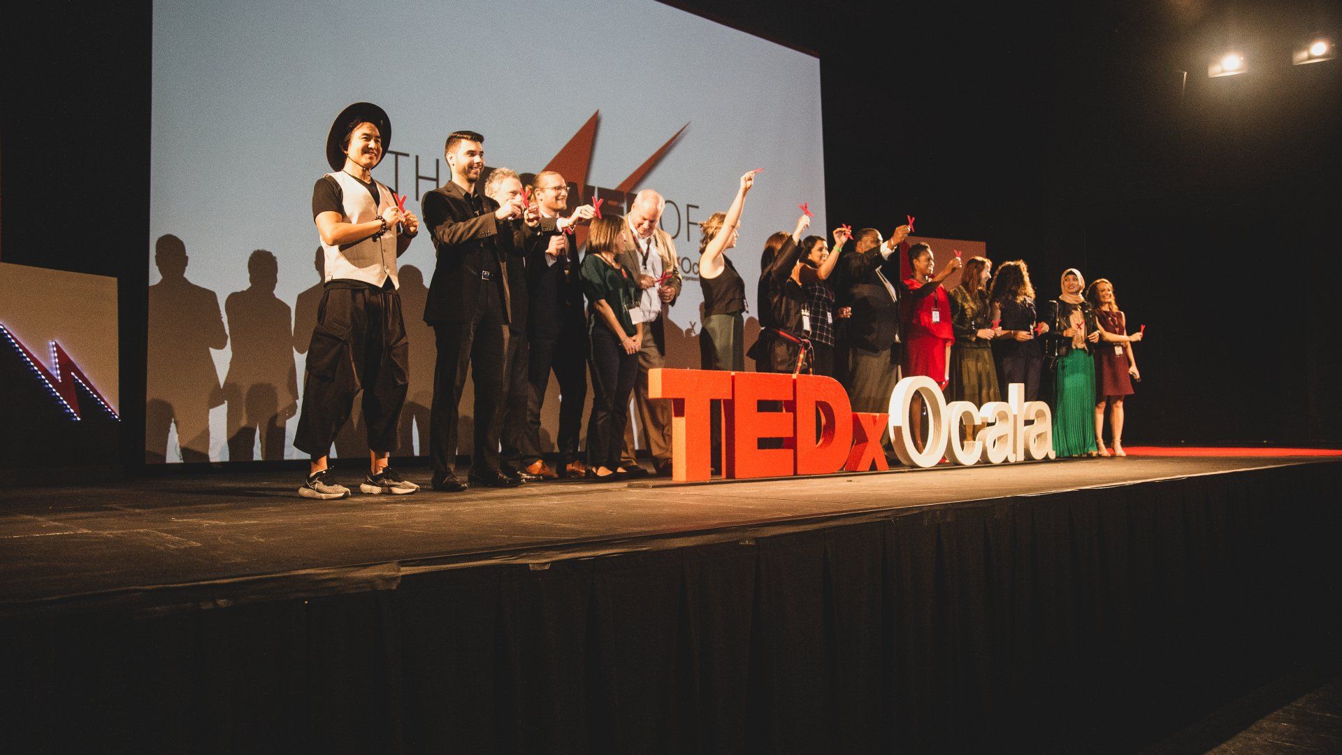 A group of people are standing on a stage in front of a ted talk sign.