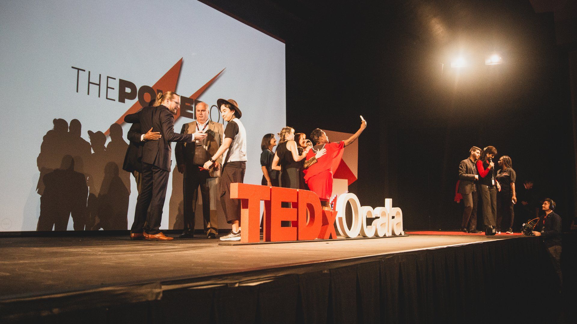 A group of people are standing on a stage in front of a ted talk sign.